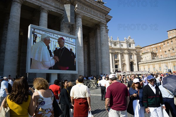 ITALY, Lazio, Rome, Vatican City Pilgrims in St Peter's Square for the wednesday Papal Audience in front of the Basilica watching Pope Benedict XVI Joseph Alois Radzinger with a cardinal on a large video TV monitor display