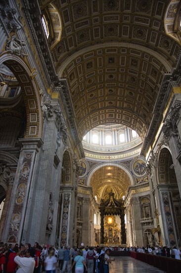 ITALY, Lazio, Rome, Vatican City Tourists in the main nave of St Peter's Basilica showing the ceiling and the Baldacchino an elaborate Baroque canopy by Bernini under the central dome