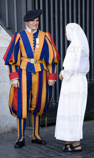 ITALY, Lazio, Rome, Vatican City A Swiss Guard in full ceremonial uniform dress talking to a nun dressed in white