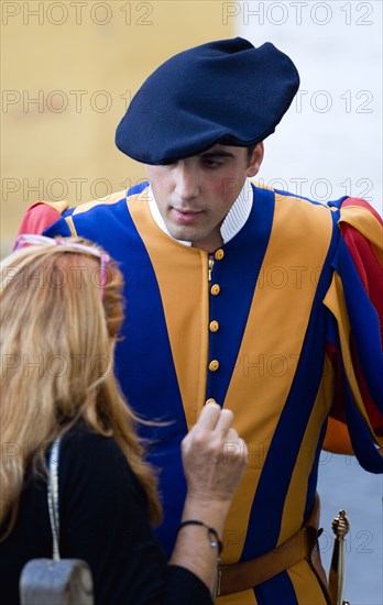 ITALY, Lazio, Rome, Vatican City A Swiss Guard in full ceremonial uniform dress talking to a female tourist