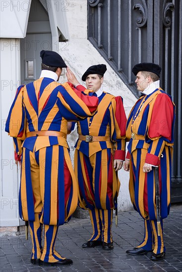 ITALY, Lazio, Rome, Vatican City Three Swiss Guards in full ceremonial uniform dress with two saluting each other