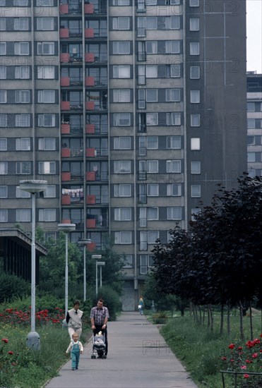 CZECH REPUBLIC, Prague, Multi-storey apartment block with young family walking along pathway in foreground.