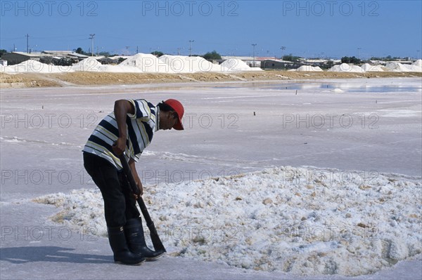 COLOMBIA, La Guajira, Manaure, Salt Mine worked by Guajiro / Wayu Indians. Male worker wearing a red baseball cap digging the salt.