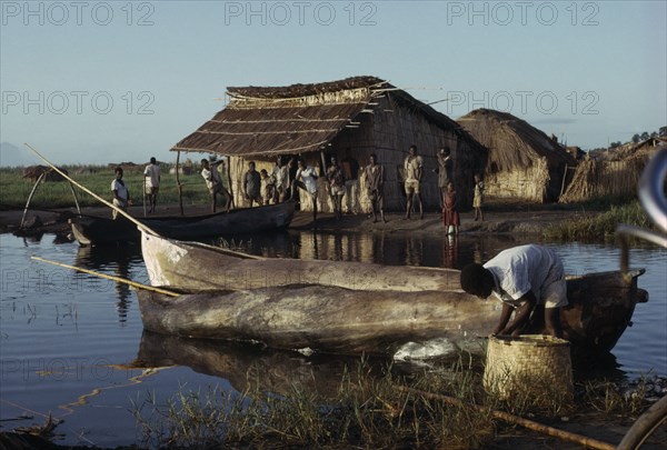 MALAWI, Chilwa, Yau tribe fishermen with Yav boats on Lake Chilwa. Men and children gathered next to thatched huts near waters edge.