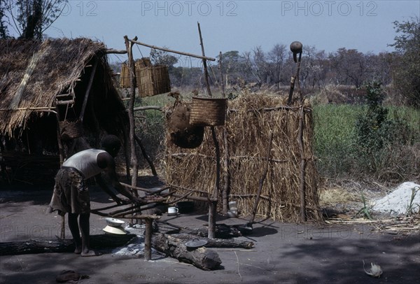 MALAWI, Tribal People, Yau Tribe, Yau village with man cooking over an open fire