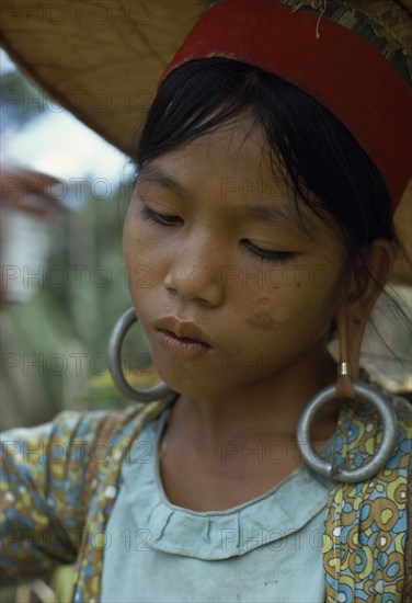 MALAYSIA, Borneo, Sarawak, Young Kayan woman harvesting dry hill rice wearing heavy earrings elongating her ear lobes and a large circular hat to protect from the sun. Subgroup of the Dayak indigenous tribes native to Borneo