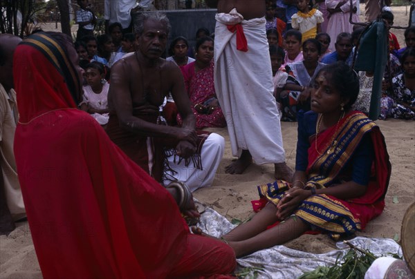 SRI LANKA, Religion, Hinduism, Punnaccolai Festival. Hindu Tamil Priest wearing a red robe performing a curing / healing Puja on a woman