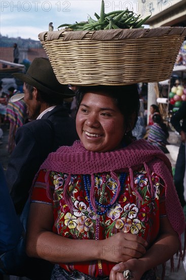 GUATEMALA, Chimaltenango , Patzun, Kaqchiquel Indian woman named Modesta smiling wearing traditional dress and carrying a basket of green beans on her head at Patzun market