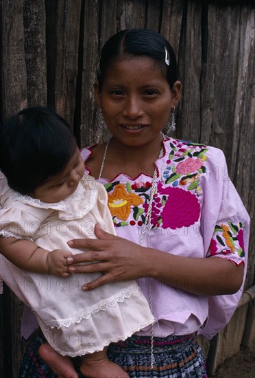 GUATEMALA, Alta Verapaz, Sacaak , Q’eqchi Indian mother wearing a traditional embroidered blouse holding her baby daughter in Sacaak refugee settlement. Roman’s daughter.