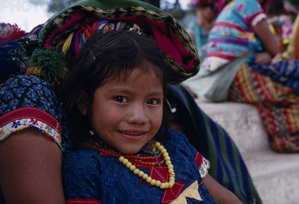 GUATEMALA, El Quiche, San Andres de Sacabaja, Portrait of a young Quiche Indian girl sitting on her mothers knee smiling