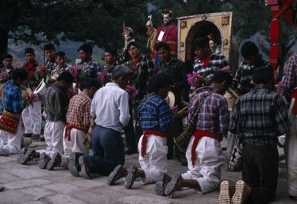 GUATEMALA, El Quiche, San Andres de Sajcabaja, Quiche Indians knelling in prayer to saints outside the 16th century church during San Andres Festival on December 8th