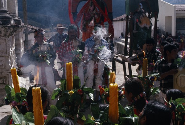 GUATEMALA, El Quiche, San Andres de Sajcabaja, Quiche Indian women holding candles facing Confradia brotherhood and Saints during San Andres Festival on December 8th