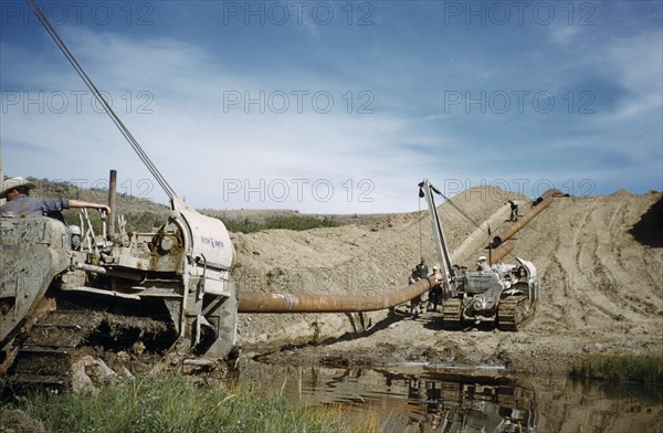CANADA, Saskatchewan , Prairies, Constructing Trans Canada gas pipeline over Saskatchewan Prairies. Workers with construction vehicles laying pipe over swamp