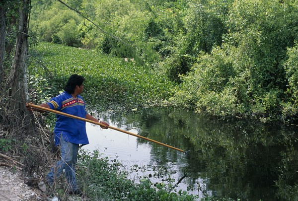 USA, Florida, Everglades, Independent Seminole Native American man named Bobby fishing with a spear in a canal next to Tamiami Highway