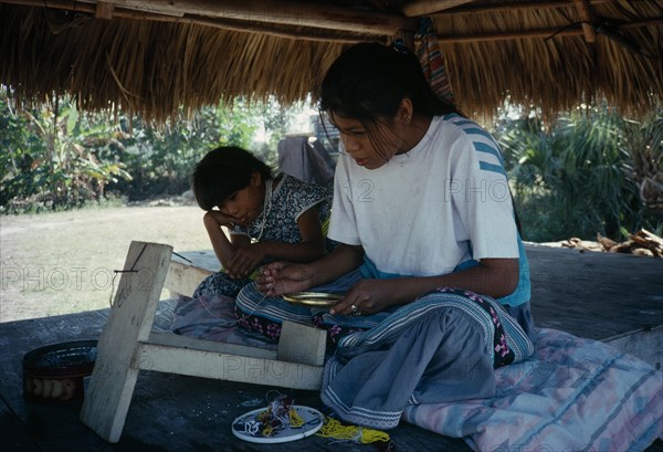 USA, Florida, Everglades, Independent Seminole Native American children making bead necklaces