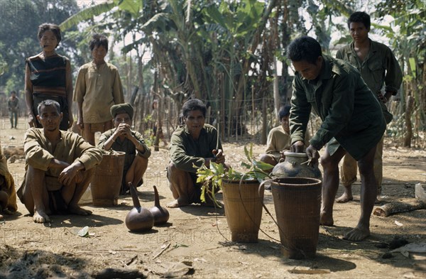 VIETNAM, Central Highlands, Pleimurong village, "Vietnam War. Montagnard village soldiers filling finely woven bamboo rice-carrier baskets, prpearing to make rice wine."