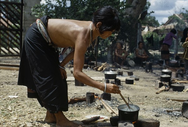 VIETNAM, Central Highlands, Kontum, Vietnam War. Montagnard village in Kontum. Refugee woman cooking rice over a small open fire