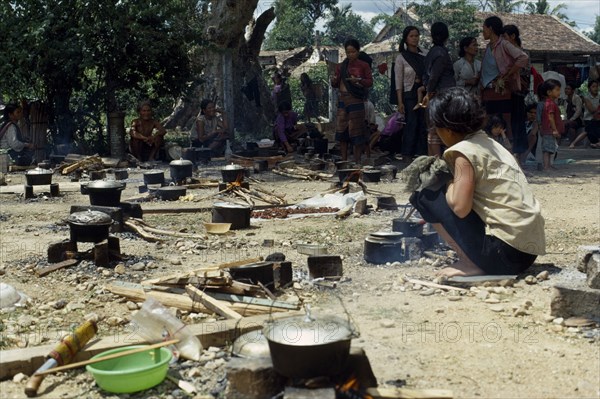 VIETNAM, Central highlands, Kontum, Vietnam War. Montagnard refugee camp in Siege of Kontum. Woman tending open fireplace  with cooking pots of rice.