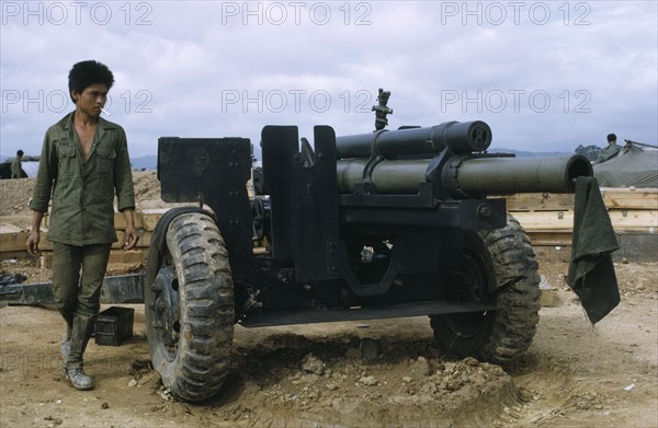 VIETNAM, Central Highlands, Kontum, Vietnam War. Siege of Kontum. Montagnard soldier next to a howitzer artillery cannon