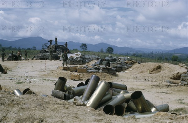 VIETNAM, Central Highlands, Kontum, Vietnam War. Siege of Kontum in Central Highlands. 20092430 Montagnard soldiers in base with empty shells from heavy artillery in the foreground