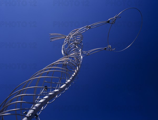 IRELAND, North, Belfast, "Oxford Street.  Angled view of modern metal sculpture from low viewpoint looking up, depicting female figure holding up hoop against cloudless blue sky."