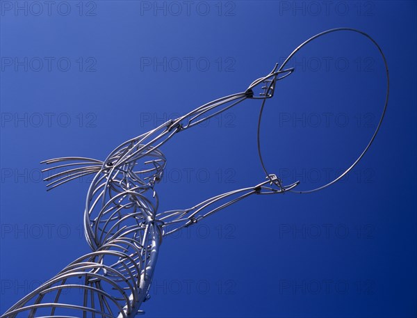 IRELAND, North, Belfast, "Oxford Street.  Angled, part view of modern metal sculpture from low viewpoint looking up, depicting female figure holding up hoop against cloudless blue sky."