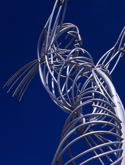IRELAND, North, Belfast, Oxford Street. Part view of modern metal sculpture depicting female figure holding up hoop against cloudless blue sky.