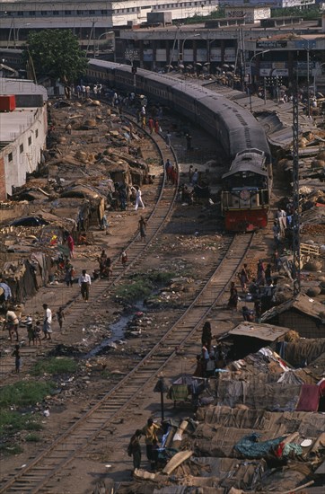 BANGLADESH, Dhaka, Train travelling through Tejgoan slum with ramshackle dwellings beside tracks and people living amongst rubbish and polluted water.