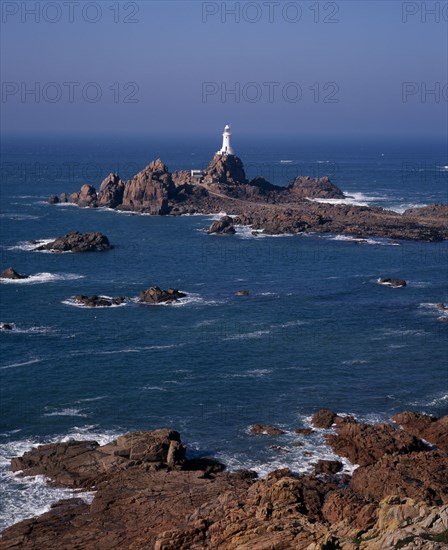 UNITED KINGDOM, Channel Islands, Jersey, St Brelade. Corbiere Lighthouse and rocky foreshore