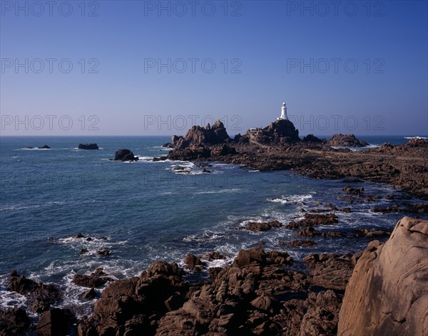 UNITED KINGDOM, Channel Islands, Jersey, St Brelade. Corbiere Lighthouse and rocky foreshore