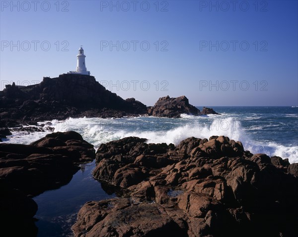 UNITED KINGDOM, Channel Islands, Jersey, St Brelade. Corbiere Lighthouse with waves crashing against rocky foreshore