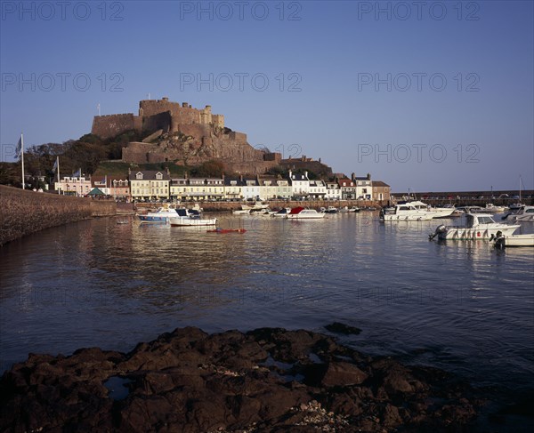 UNITED KINGDOM, Channel Islands, Jersey, Grouville. Gorey Castle or Mont Orgueil set on hill overlooking village buildings and boats in harbour with the tide in. On the east coast.