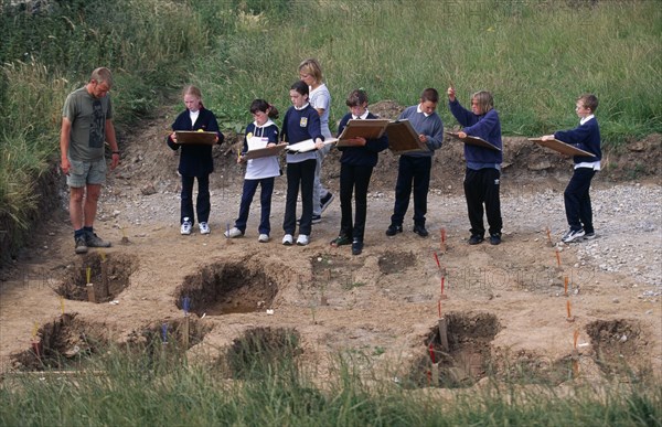 ENGLAND, Yorkshire, Whitby Abbey, Students and teacher on school field trip at archaeological dig in the graveyard at Whitby Abbey founded by St Hilda AD657.
