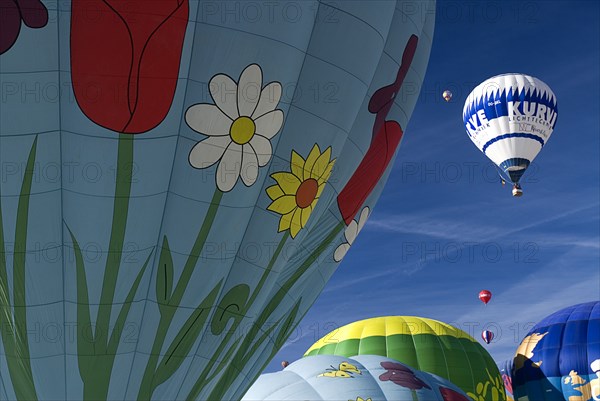 SWITZERLAND, Canton de Vaud, Chateau d'Oex, Three Hot Air Balloons taking off and framed by sections of other balloons.