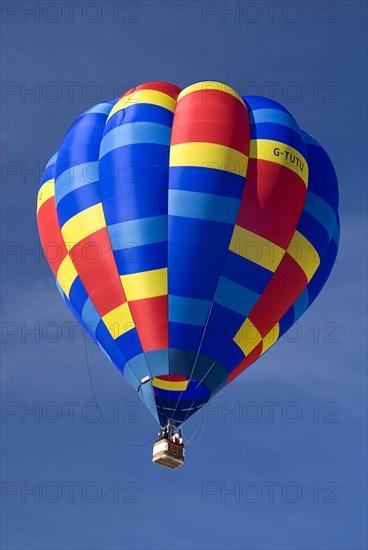 SWITZERLAND, Canton de Vaud, Chateau d'Oex, Single colourful Hot Air Balloon as it ascends after take off.