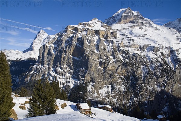 SWITZERLAND, Bernese Oberland, Murren, Houses on cliff edge with Eiger and Monch mountains in background.