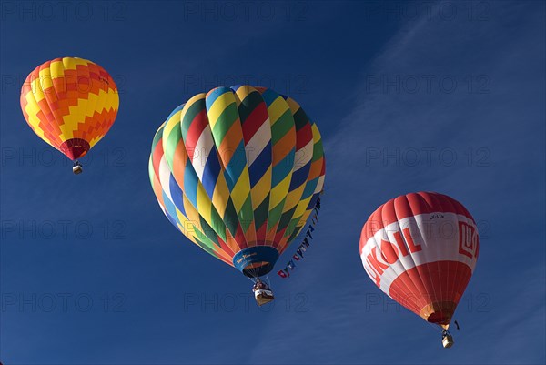 SWITZERLAND, Canton de Vaud, Chateau d'Oex, Three Hot Air Balloons in line ascending into a blue sky