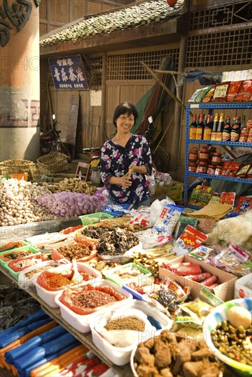 CHINA, Sichuan Province, Chongqing, "Street market with a smiling woman vendor selling spices, garlic, ginger and other foodstuffs below Ciqiikou Ancient Town"