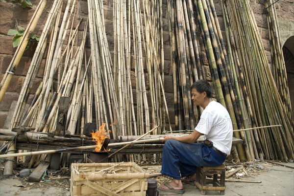 CHINA, Sichuan Province, Chongqing, Man strengthening bamboo joints with fire