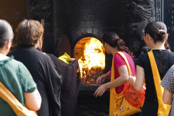 CHINA, Zhejiang , Putuoshan, Puji Temple outer courtyard. Burning incense packaging material and other garbage