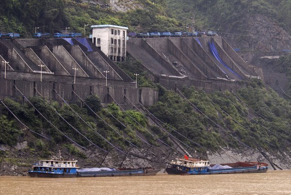 CHINA, Hubei , Sandouping, Industrial complex in the Wu Gorge. Line of trucks bring coal from the mines and dump into bunkers from where it flows through pipes to coal barges waiting below on the Yangtze River