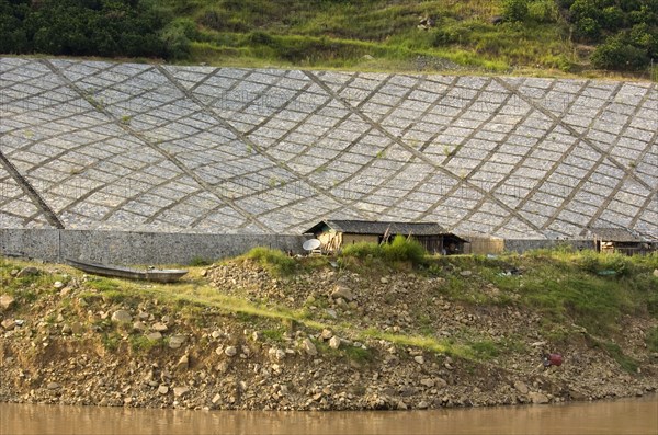 CHINA, Chongqing , Yangtze, Stone lining the Yangtze River embankment near Wushan with satellite TV dish by worker's temporary living quarters