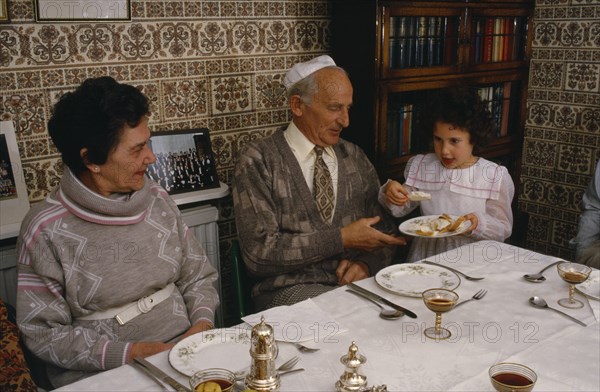 ENGLAND, Religion, Judaism, "Jewish New Year meal, young girl passing the chala or bread to family members."
