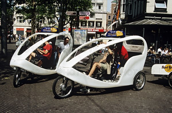 HOLLAND, Amsterdam , Wieler taxis and tourists waiting in a square