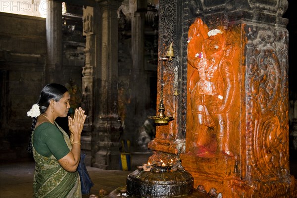 INDIA, Tamil Nadu, Madurai, "Female worshiper praying beside a shrine, Meenakshi Temple"