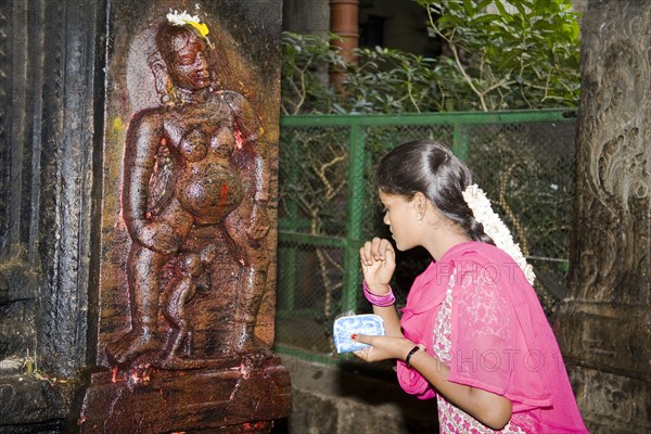 INDIA, Tamil Nadu, Madurai, "Young woman standing beside shrine depicting Goddess of Fertility, Meenakshi Temple"