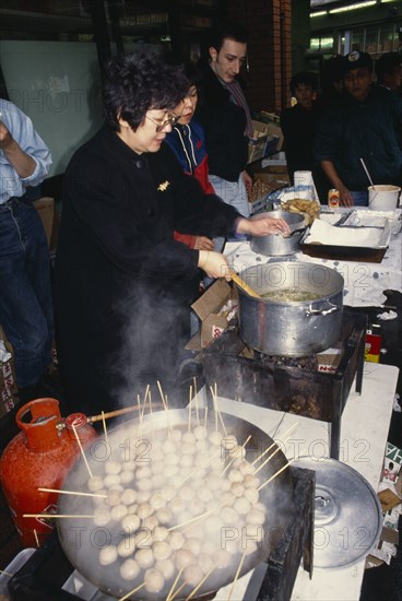 ENGLAND, London, Chinese New Year, Women cooking on street stall during New Year celebrations in Chinatown.