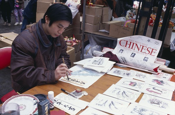 ENGLAND, London, Chinese New Year, Chinese painter working at stall during New Year celebrations in Chinatown as part of ‘East Meets West’ painting exhibition.