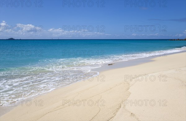 WEST INDIES, St Vincent And The Grenadines, Canouan Island, South Glossy Beach in Glossy Bay with waves breaking on the shoreline of the turqoise sea.