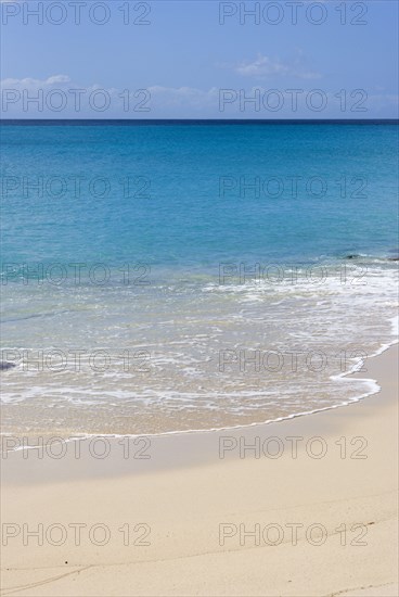 WEST INDIES, St Vincent And The Grenadines, Canouan Island, South Glossy Beach in Glossy Bay with waves breaking on the shoreline of the turqoise sea.